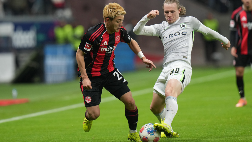 Frankfurts Offensivmann Ritsu Doan (l.) und der Wolfsburger Patrick Wimmer (m.) im Duell um den Ball.