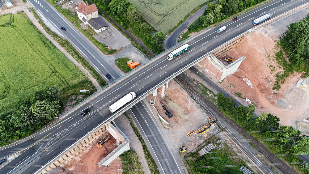 Luftbild der Brückenbaustelle der A7 über die B62 und die Bahngleise bei Niederaula. Der Verkehr läuft mit zwei Fahrstreifen je Fahrtrichtung (sog. 4+0 Verkehrsführung) über das östliche Teilbauwerk (Richtungsfahrbahn Kassel). Das westliche Teilbauwerk (mit der Richtungsfahrbahn Würzburg) ist bereits zurückgebaut.