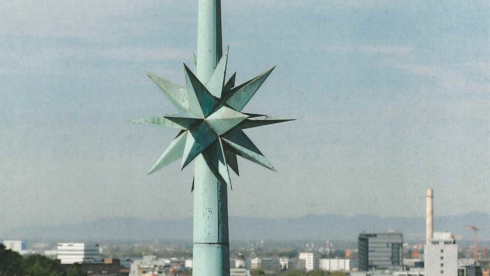 Auf dem Bild ist die gestohlene Turmspitze mit Stern zu sehen, im Hintergrund die Stadt.