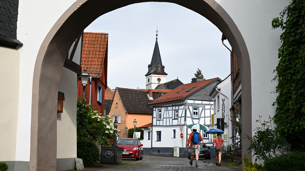 Paar läuft mit Regenschirmen durch ein altes Stadttor im Taunus.