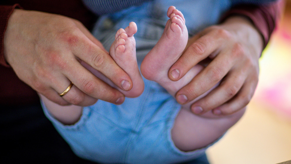 Hände halten die Füße von einem Baby
