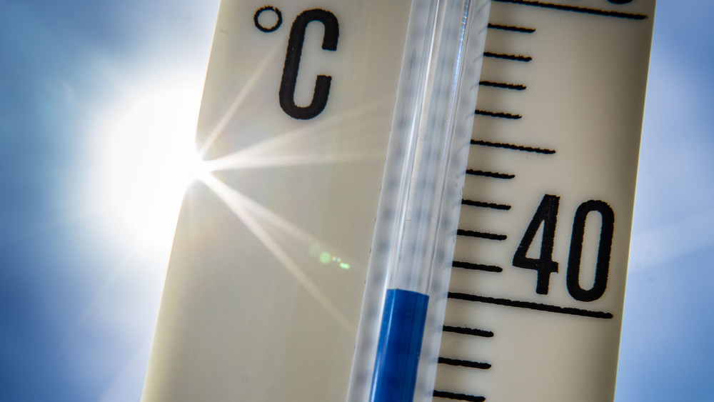 Ein Außenthermometer zeigt vor dem blauen Himmel und der Sonne eine Temperatur von nahezu 40 Grad Celsius an