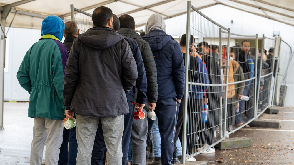 Flüchtlinge warten in einer Schlange vor der Essensausgabe (Symbolbild).