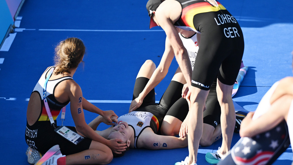 Laura Lindemann (unten) liegt nach dem Zielsprint im Ziel und wird nach dem Olympiasieg von den Teamgefährten Lisa Tertsch (l), Lasse Lührs (r) und Tim Hellwig (2vr) umjubelt.