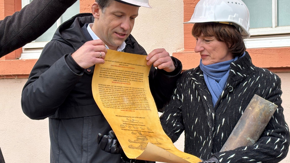 Der Mainzer Oberbürgermeister Haase und Baudezernentin Grosse zeigen das Dokument, das sich in einer Zeitkapsel unter dem Schellbau befand.