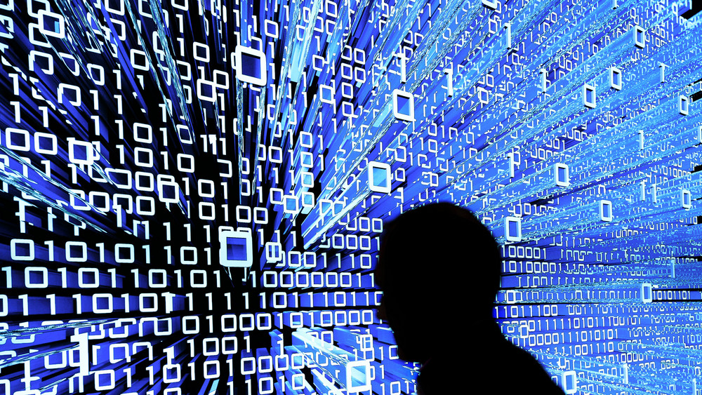 Ein Messebesucher geht an einem Leuchtdisplay auf der CeBIT vorbei