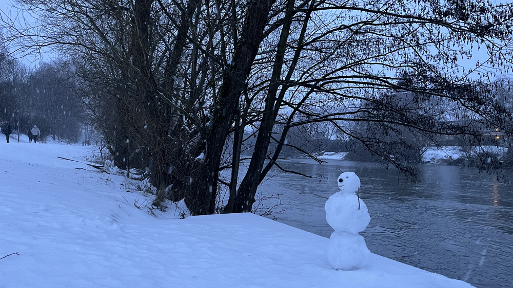 Ein Schneemann wendet der Lahn in Gießen den Rücken zu.
