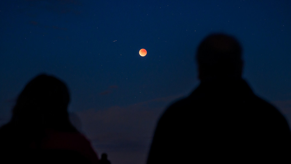 Zwei Personen beobachten eine totale Mondfinsternis