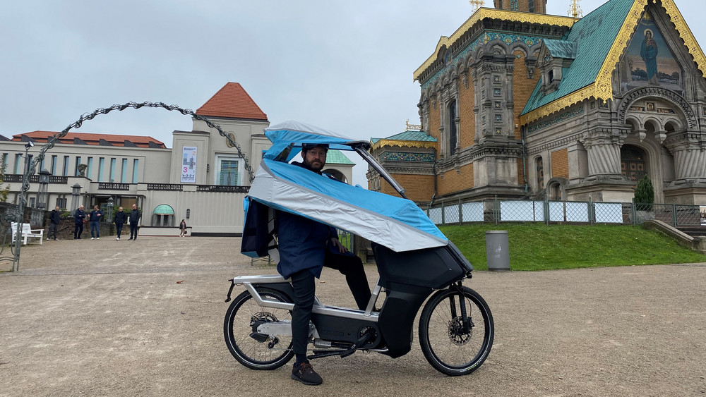 Robert Toroczkay von der Hochschule Darmstadt auf dem Pendler-Bike-Prototyp vor der Kulisse der Mathildenhöhe