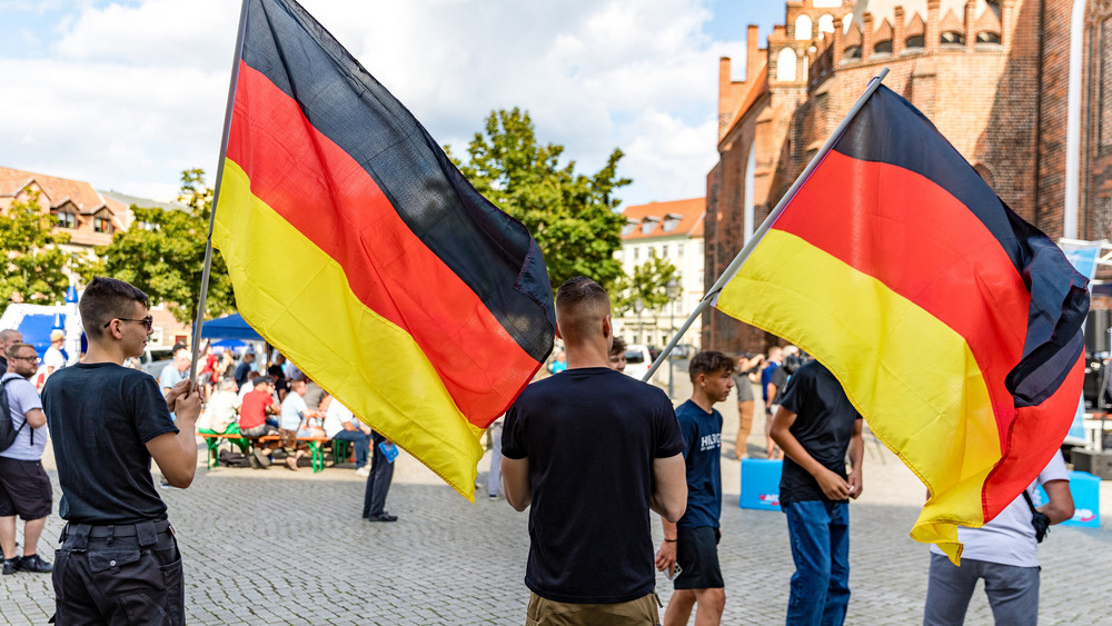 Mitglieder der Jungen Alternative, der Nachwuchsorganisation der AfD, schwenken auf einer Wahlkampfveranstaltung der AfD Brandenburg in Cottbus Deutschlandfahnen.