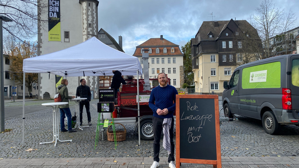 Vorstandsvorsitzender Lukas Duraj steht vor der mobilen Suppenküche auf dem Gießener Marktplatz.