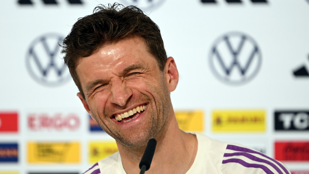 Deutschlands Thomas Müller lacht bei der Pressekonferenz. 