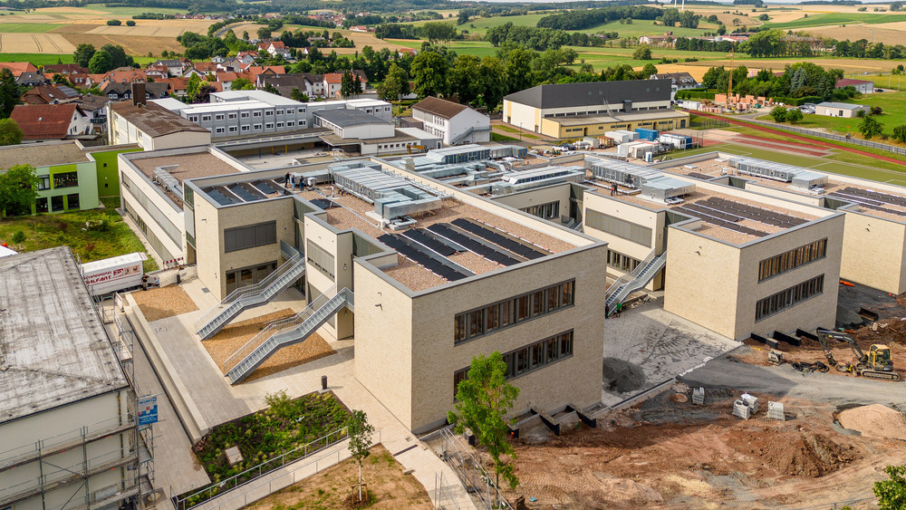 Vorne der Neubau, im Hintergrund der Containerbau, in dem die Schülerinnen und Schüler in den vergangenen drei Jahren unterrichtet wurden. 