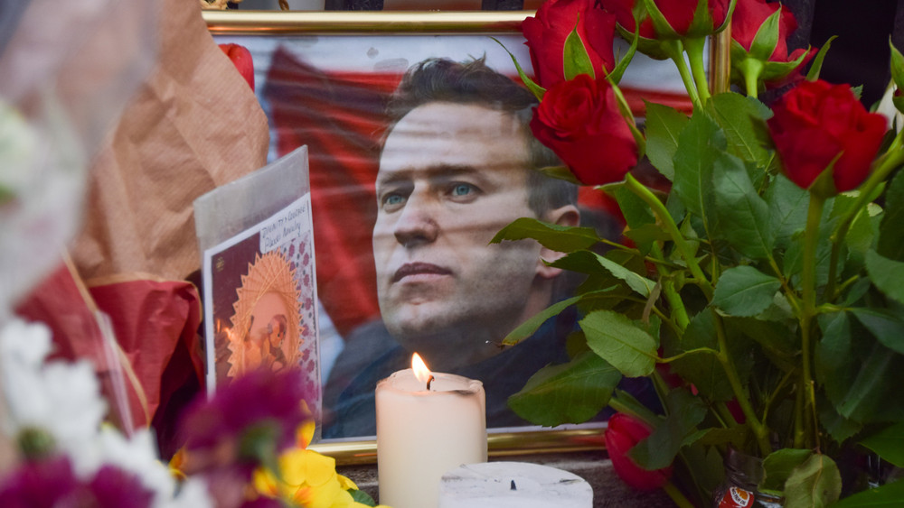 An einer behelfsmäßigen Gedenkstätte gegenüber der russischen Botschaft stehen Blumen, Kerzen, und Karten um ein gerahmtes Foto von Alexej Nawalny. Der russische Oppositionsführer starb am 16.02.2024 im Alter von 47 Jahren nach Angaben der Justiz in einem sibirischen Straflager.