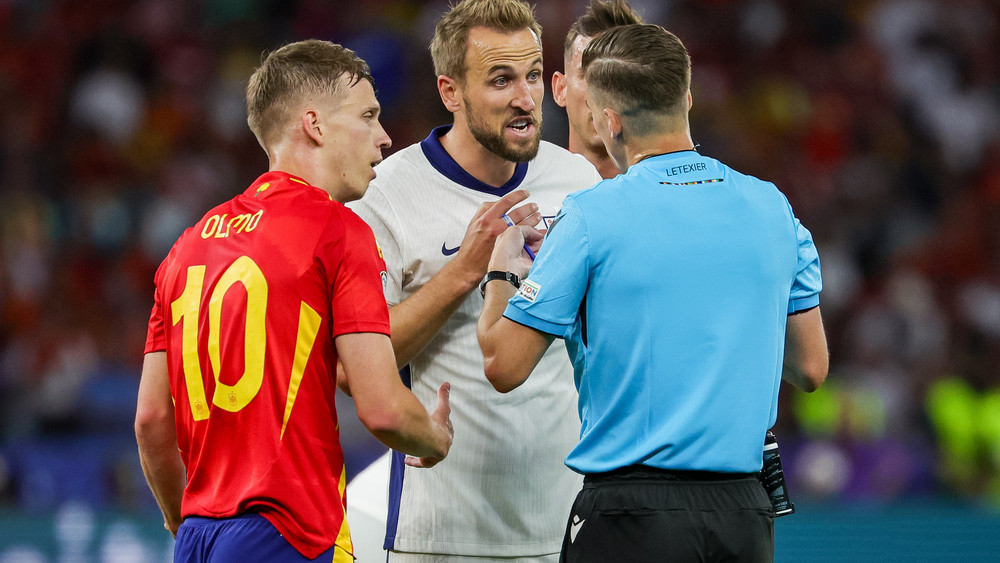 Spaniens Dani Olmo (l) und Englands Harry Kane diskutieren mit Schiedsrichter Francois Letexier aus Frankreich beim EM-Finale 2024.