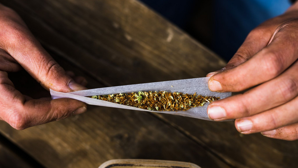 Ein Mann dreht sich mit Cannabis und Tabak einen Joint