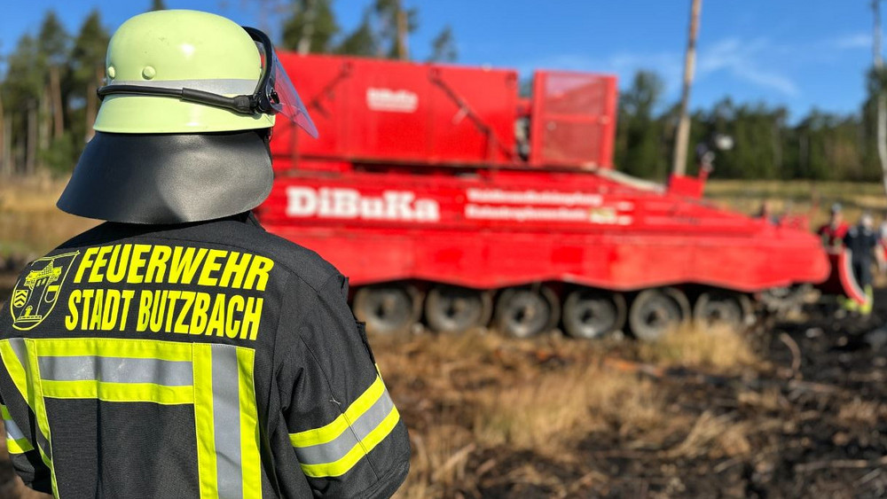 Ein Feuerwehrmann aus Butzbach. Im Hintergrund bereitet sich der Löschpanzer auf den Einsatz vor. 